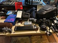 Overview of lot on table including cameras, viewer, flash, film, SD card and cases