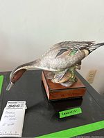 Full side view of the ceramic mallard duck showing body and wooden base.