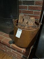 Copper bucket filled with firewood placed on brick hearth.
