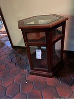 Front side view showing the hexagon display cabinet's dark wooden frame, glass panels, and locking door with key.