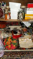 Multi-level shelf of various sewing items including thread spools, buttons in jars and tins, a red decorative tin, and fabric pieces.