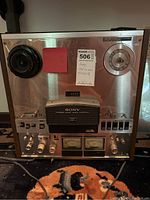 Front view of Sony reel to reel tape recorder showing metal panel with tape reels holders, control knobs, buttons, meters, and analog counter. Sony branding and model visible.