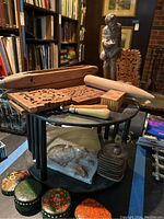 Full lot view on small round black table including lacquered boxes, coasters, wooden statue, weaving tools and carved wooden panels