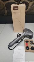 Full item lot with the handheld dual percussion massager, three pairs of interchangeable massage heads in cardboard tray, user manual, and original box with product description and NAIPO branding.