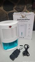 Photo showing the front of the Letsport household dehumidifier with attached water tank and original box in the background.
