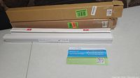 Two boxed sets of cellular shades and two white mounting strips laid out flat on a surface.