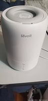 Front view of the Levoit Dual 100 humidifier showing the white cylindrical design and brand name on the front.