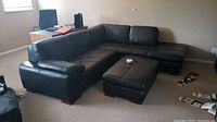 Full view of three-piece black leather sectional with ottoman