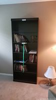 Front view of the dark wood 6-shelf bookcase with some books on shelves showing size and structure.
