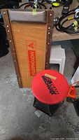 Photo showing the top side of the Motomaster wooden creeper and the red Team Mechanix rolling work stool seat.