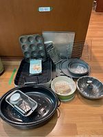 Photo showing entire lot from front including muffin pan, roasting pan, round cake pans, baking tools and racks.