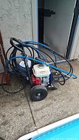 Pressure washer assembled on frame with coiled hoses, engine and pump visible