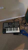 Akai MPK25 keyboard on carpet with microphone and cables.