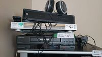 Full view of stacked electronics showing Sony CD/DVD player, Motorola receiver, Emerson VCR, and headphones on top.