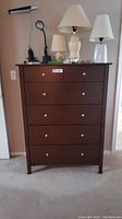 Front view of the dresser showing six closed drawers with silver knob handles and a dark brown wood finish.