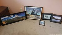 Full view of all five framed art prints arranged on carpet, showing varied landscape and wildlife themes in black and wood-toned frames.