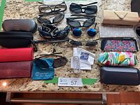Overview of assorted sunglasses and eyeglass cases arranged on a marble countertop