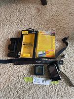 Overview photo showing OtterBox case, Polar watch, Polar chest strap, Garmin Golf Buddy, Bushnell rangefinder, and car holder on carpet.