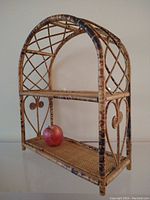 Front view of bamboo and wicker shelf with apple placed on lower tier for scale.