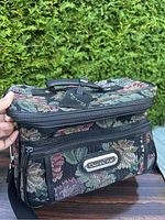 Full view of the rectangular Oscar De La Renta tapestry bag showing floral design and main compartments with zippers and handle on top.