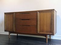 Front view of closed walnut buffet showing drawers and cabinet doors on tapered legs