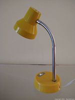 Front view of yellow adjustable desk lamp showing conical shade, flexible chrome goose neck, rounded base with integrated switch, and white power cord.