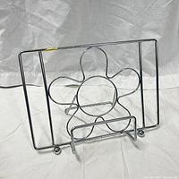 Front view of silver metal bookstand showing flower motif and base ledge