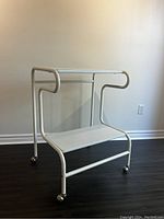 Full view of the white tubular metal cart showing its rectangular frame and shelf.