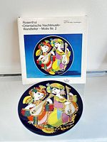 Photo showing the original box with the full product title and artwork, alongside the decorative plate itself.