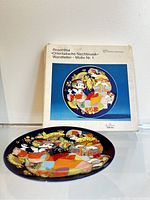 Image showing the Rosenthal plate in front of original packaging with colorful design and German text.