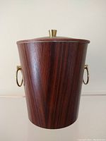 Front view of the rosewood ice bucket with brass handles and lid knob.