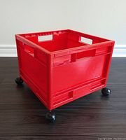 Full view of the red IKEA plastic storage crate on black spherical caster wheels, showing overall condition.
