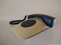 Front view of vintage 1980s post modern telephone showing cream-colored base, black handset, and push-button dial pad.