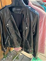 Guess black leather motorcycle jacket hanging on hanger, showing front and detailing