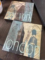 Two square canvas art pieces featuring New York and London scenes with text.