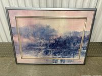 Framed watercolor painting showing misty lake scene with loons, soft pastel blues and pinks, encased in silver frame with gold and white matting.