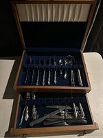 Full view of wooden box containing vintage cutlery with many compartments and various utensils inside.