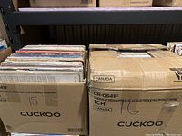 Two cardboard boxes filled with vinyl records viewed from the top, showing stacked album covers.