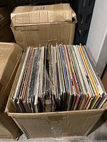 Photo of second box filled with vinyl records, also showing a variety of album sleeves and edges, box labeled '29'.
