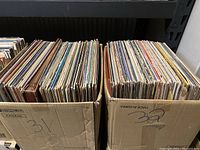 Two cardboard boxes labeled '31' and '32' filled with vinyl LP records stored upright in their sleeves.
