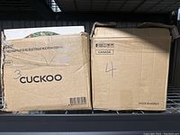 Two cardboard boxes labeled with numbers 3 and 4 containing vinyl records, one branded 'Cuckoo' and marked 'Made in Korea'.