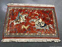 Full view of carpet on concrete floor showing red field, white fringes and border