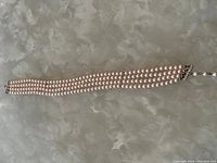 Full view of the three-strand faux pearl necklace laid on a white textured surface.