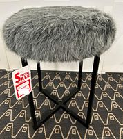 Full view of the gray faux fur seat on black metal legs stool showing the plush texture and round seat shape.