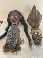 Overview photo showing all four carved masks with varied facial styles and adornments.