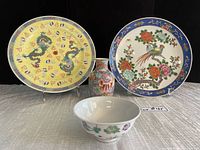 Front view of both plates, bowl and vase against black background