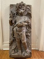 Front view of angel wall plaque showing details including angel's face, wings, lamb, and sheaf of wheat.