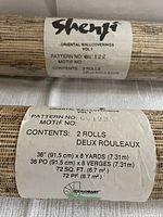 Close up of label on the wallpaper roll showing Shengji branding, Oriental Wallcoverings Vol 1, pattern number GN 122, dimensions 36 inches by 8 yards, two rolls included.