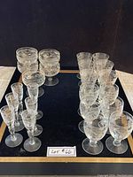 Full set of 23 assorted antique ribbed and engraved glasses displayed on black surface.