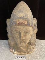 Front view of the large antique wooden head sculpture showing the facial features, headdress, and surface wear.